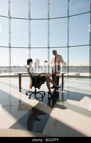 La gente di affari che lavorano in uffici di grandi dimensioni con parete in vetro Foto Stock