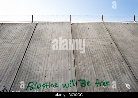 Il graffiti slogan "Palestina sarà gratuita' è dipinta sulla separazione israeliano della barriera 8 metro di altezza parete di cemento. Foto Stock