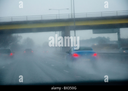 Driver vista attraverso un parabrezza di automobile che mostra condizioni di marcia difficili, e di scarsa visibilità (spray e la nebbia) su un'autostrada. Foto Stock