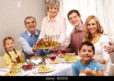 Ritratto della grande famiglia seduti a tavola festiva e guardando la telecamera con un sorriso Foto Stock