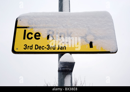 Coperta di neve segno sulla lampada post che mostra le direzioni alla pista di pattinaggio sul ghiaccio Foto Stock