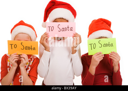 Dei bambini felici come nascondere le loro facce dietro le buste con la nota "Santa" Foto Stock