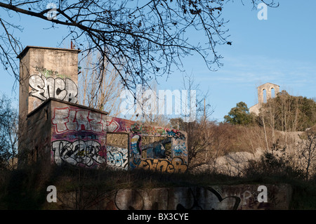 Coperto di graffiti vestigio industriale e la romanica chiesa di Saint Etienne d'Issensac, Francia meridionale Foto Stock