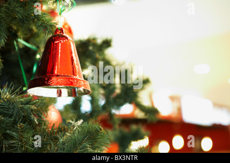 Close-up di rosso campana giocattolo appeso sul verde ramo di abete rosso Foto Stock