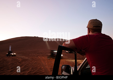 L'uomo guarda la 4x4s sul Big Red dune di sabbia a Dubai, Emirati arabi uniti Foto Stock