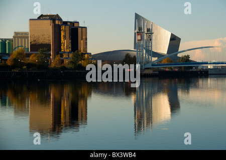 Il Quay West edificio, Imperial War Museum North e il Millennium footbridge a Salford Quays, Manchester, Inghilterra, Regno Unito Foto Stock