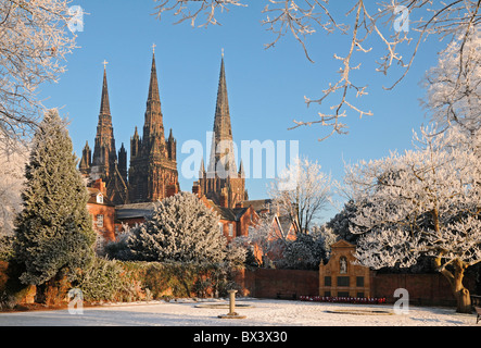 Lichfield Cathedral di St Chad con tre guglie visto dal Memorial Garden in inverno con trasformata per forte gradiente il gelo e la neve sotto il cielo blu Foto Stock