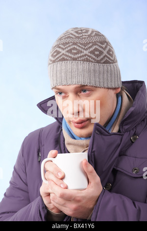 Ritratto di giovane uomo in vestiti caldi di bere tè o caffè caldo Foto Stock