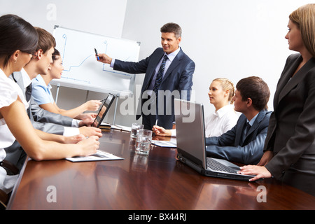 Immagine della Smart Business persone che guardano il loro leader mentre lui spiegare qualcosa su whiteboard durante il seminario Foto Stock