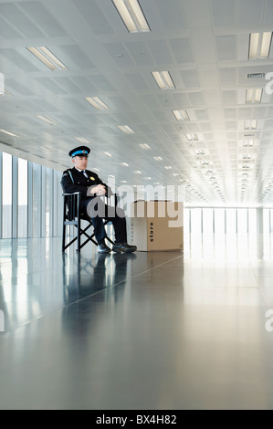 Guardia in uniforme seduto nel vuoto dello spazio ufficio Foto Stock