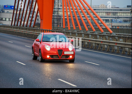 Auto rossa la guida in città sul ponte del cavo, Riga, Lettonia Foto Stock