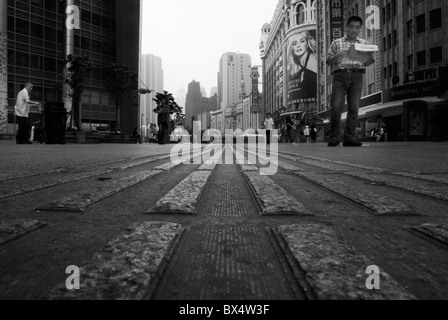 Shanghai - pavimentazioni tattili prospettiva sulla pedonale quotidiano di lettura mentre si cammina attraverso la Nanjing Road shopping street Foto Stock