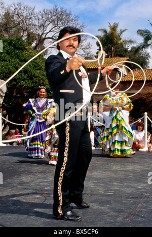 Un messicano di ballerini folk esegue una danza lariat usando un lazo a California folk festival. Nota le donne in costume nativo. Foto Stock