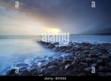 Tramonto sulla tempesta del giorno guardando attraverso Kimmeridge Bay da resti di Clavell è Pier, Kimmeridge, Dorset, England, Regno Unito Foto Stock