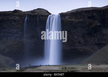 Cascata Seljalandsfoss catturato al crepuscolo mediante esposizione a lungo per registrare il movimento in acqua, vicino a Hella, area meridionale, Islanda Foto Stock