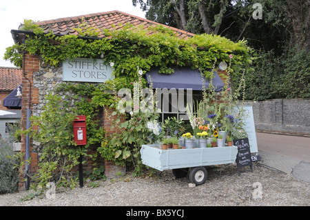 I negozi del villaggio e un ufficio postale con i fiori per la vendita al di fuori, Stiffkey, Norfolk, Regno Unito, Agosto Foto Stock