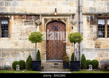 Casella ritagliata e baia alberi al di fuori di una pietra di Cotswold House di Broadway, Worcestershire Foto Stock