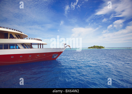 Giovani saltando da una barca in mare, Maldive, Oceano Indiano, Asia Foto Stock