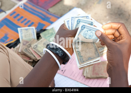 Una donna conta Dollaro liberiano in Kakata, Liberia, Africa occidentale. Foto Stock