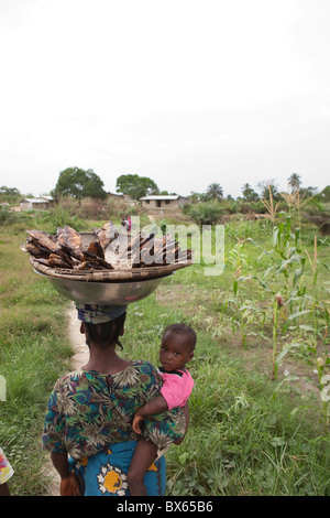 Una madre porta un cesto di pesce con sua figlia in Kakata, Liberia, Africa occidentale. Foto Stock