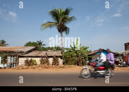 Un motociclo ingrandisce la strada a Monrovia, Liberia, Africa occidentale. Foto Stock