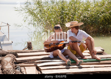 Coppia giovane seduti insieme sul molo Foto Stock