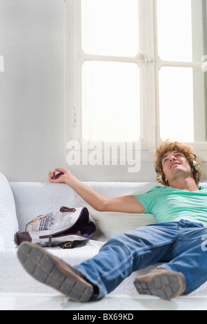 Giovane Uomo con cuffie giace sul lettino Foto Stock