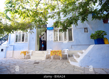 Il Greco antico donna vestita di nero in uscita di una taverna nel villaggio di Arnados, sul Greco Cyclade isola di Tinos. Foto Stock