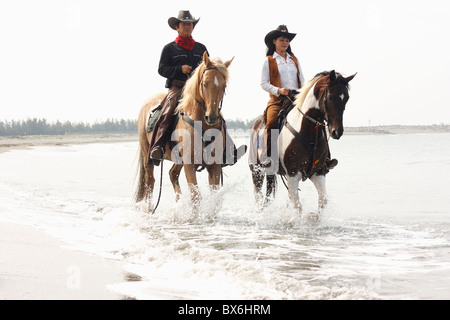 Due persone corsa dei cavalli insieme in spiaggia. Tainan, Taiwan Foto Stock