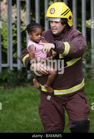 Fireman salvataggi di un piccolo bambino da un incendio Foto Stock