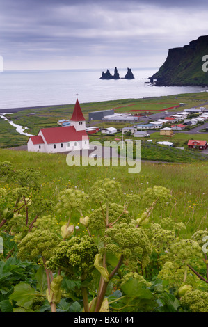 La chiesa ed il villaggio di Vik (Vik un Myrdal) e mare Reynisdrangar pile in distanza, costa sud dell'Islanda (Sudurland), Islanda Foto Stock