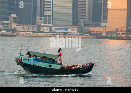 Sampan voce attraverso il Victoria Harbour in mattinata con la skyline di Kowloon in background, Isola di Hong Kong, Cina Foto Stock