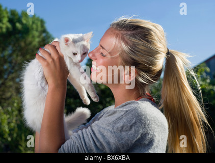 Giovane donna sorrisi holding gattino Foto Stock