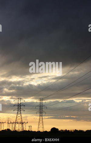 Torri di trasmissione e linee di alimentazione stagliano contro un tramonto spettacolare sky. Stanislaus County, California, U.S.A. Foto Stock