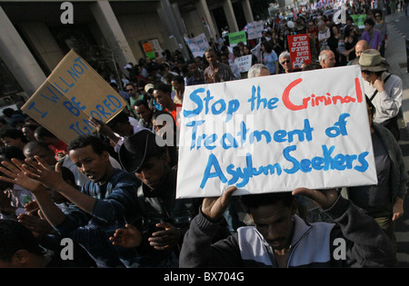 Un manifestante ha in mano un segno che recita "Stop al trattamento criminale dei richiedenti asilo" durante un raduno organizzato da migranti africani e attivisti israeliani che segnano i diritti umani internazionali a Tel Aviv in Israele Foto Stock