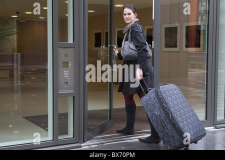 Donna borsa di trazione attraverso la porta Foto Stock