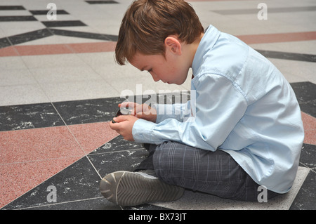 Giovane ragazzo giocando con il suo Ipod palmare Foto Stock