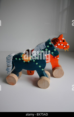 Due giocattolo per bambini è cavalli in legno dipinto in colori luminosi sulla parte superiore della superficie bianca. Foto Stock