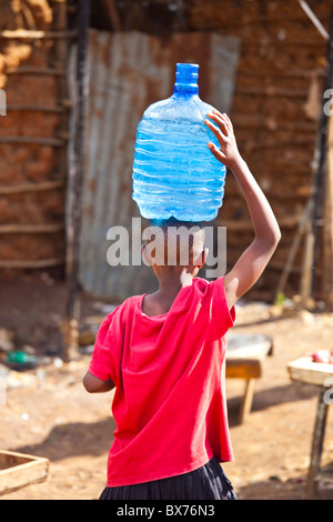 Ragazzo che trasportano l'acqua nella baraccopoli di Kibera, Nairobi, Kenia Foto Stock