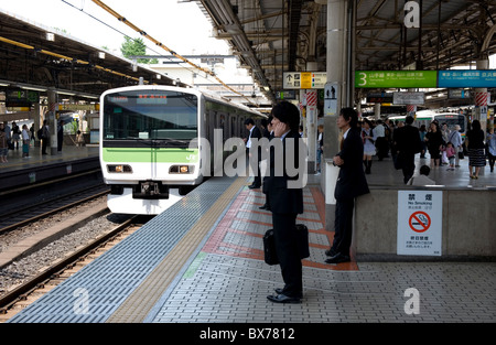 Imprenditore in attesa per il loop di Yamanote Line solo in treno arrivando alla stazione JR Ueno stazione ferroviaria in Tokyo, Giappone, Asia Foto Stock