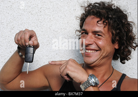 Giovane uomo in possesso di una chiave auto e con orgoglio sorridente Foto Stock