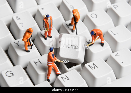 Lavoratore statuine poste intorno il tasto Home sulla tastiera di un computer. Foto Stock