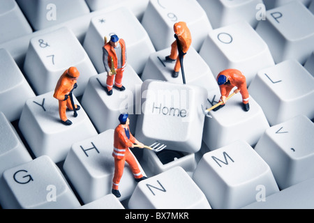 Lavoratore statuine poste intorno il tasto Home sulla tastiera di un computer. Foto Stock