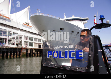 La polizia di Vancouver Unità Marine imbarcazione di pattuglia nei pressi di una nave da crociera nave in Vancouver, British Columbia, Canada Foto Stock