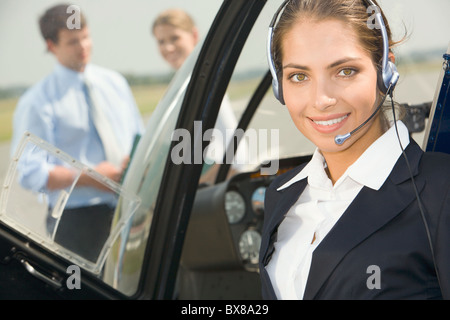Fiducioso pilota con auricolare sorridente in elicottero privato Foto Stock