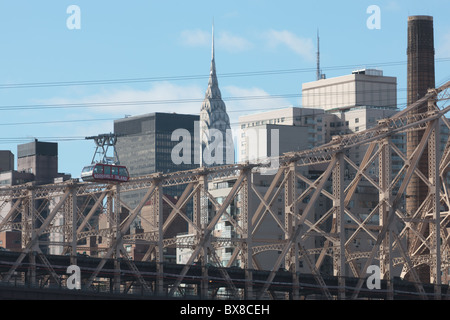 Il Roosevelt Island Tram attraversa la East River con il Queensboro Bridge e dello skyline di Manhattan in background in New York City. Foto Stock