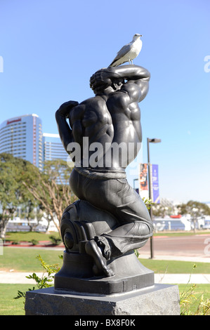 Un uccello si siede su una statua in bronzo nella luce di Gas Lamp District del centro cittadino di San Diego, California, vicino al porto Foto Stock
