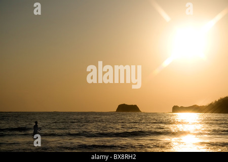 Tramonto con attività di pesca nell'oceano Pacifico a Playa Carrillo vicino Samara, Costa Rica. Foto Stock