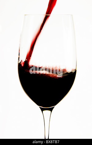 Versare il vino rosso in un bicchiere da degustazione Foto Stock