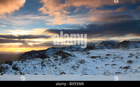 Gli inverni giorno volge al termine, mentre il sole tramonta dietro Scafell Pike, Englands montagna più alta. Foto Stock